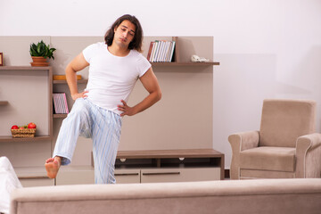 Wall Mural - Young lazy man in oversleeping concept at home