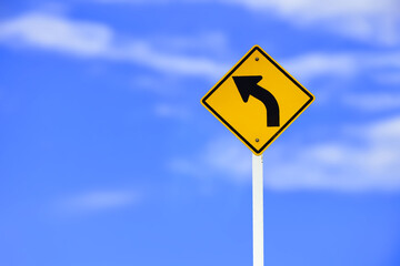 Left turn sign on white pole with clouds and blue sky background.