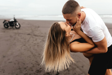 Wall Mural - Young couple riders together on sand beach by motorbike - travel concept