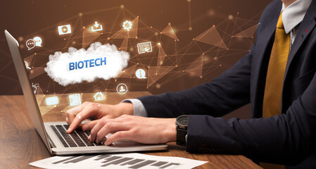 Businessman working on laptop with BIOTECH inscription, modern technology concept