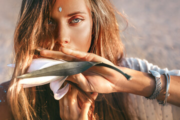 beautiful young stylish woman close up portrait with orchid flower at sunset