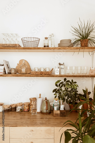 Obraz Dibond Modern boho style home kitchen interior concept. Wooden shelfs, dishes, utensils, decorations. Cozy comfortable bohemian interior design.