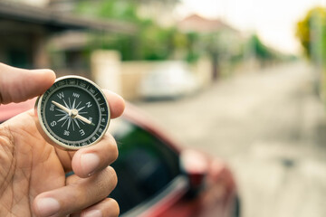 Man hand holding compass on city and car blurred background Using wallpaper or background travel or navigator image.