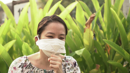 Asian woman wearing mask looking ill cough corona a allergy symptom green background