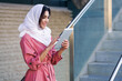© javiindy - Young Muslim woman wearing hijab using digital tablet outdoors