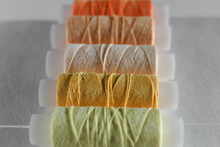 A Set Of Sewing Thread Reels On A White Background. Yellow Thread. Several Coils Of Thread In Different Shades Of Yellow And Beige. Background With Yellow Spools Of Thread. Selective Focus