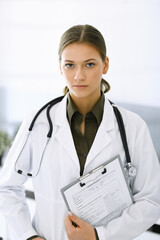 Wall Mural - Woman-doctor standing and looking at camera. Perfect medical service in clinic. Medicine and healthcare