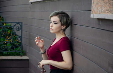 Wall Mural - The girl stands against the background of a wall of wooden canvases