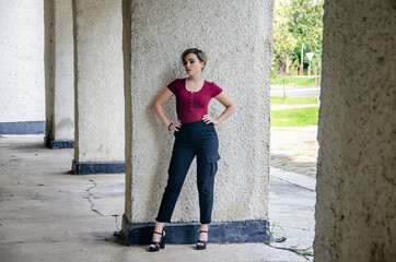 Wall Mural - A girl in a red jacket stands against the background of a concrete column