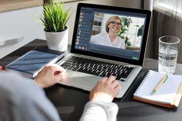 Woman having video conference with colleagues at table. Multiethnic business team working from home using laptop, discussing financial report of their company.