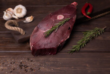 Raw Fresh Meat On A Wooden Background. Venison With Red Pepper And Rosemary. Garlic And Seasonings. Cooking A Delicacy Of Deer Meat. Venison Has High Taste And Vitamin Properties. Healthy Diet.