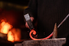 Blacksmithing. The Blacksmith On The Anvil Measures The Width Of The Split Product And Glowing Sparks Fly In All Directions. Photo Of Red Metal Close-up.