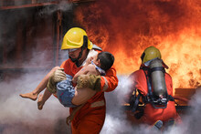 Firefighter Holding Child Boy To Save Him In Fire And Smoke,Firemen Rescue The Boys From Fire.