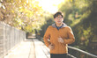 © NVB Stocker - Asian Man in yellow hoodie jogging and running beside road in park at autumn morning.