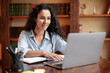 © Prostock-studio - Woman sitting at table, using computer and typing on keyboard