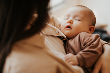 Young mother holding her newborn child. mother's care baby. Woman and new born girl relax. Baby sleeping on mom's arms