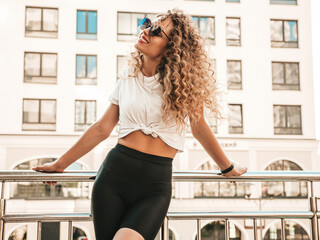 Portrait of beautiful smiling model with afro curls hairstyle dressed in summer hipster clothes.Sexy carefree female posing in the street background. Trendy funny and positive woman having fun