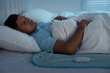 Man sleeping on electric heating pad in bed at night