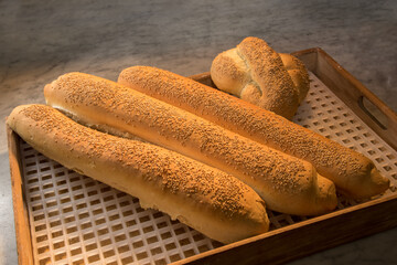 Freshly baked loaves with sesame seeds. Baguette bread in wooden tray