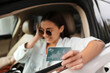 © New Africa - Woman sitting in car and showing credit card at gas station, focus on hand