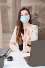 Young woman with protective mask on her face is standing at the office table.
Secretary wears mask in the office. Social distance