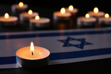 Burning Candle And Flag Of Israel On Black Table. Holocaust Memory Day