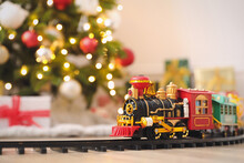 Toy Train And Railway Near Christmas Tree Indoors. Space For Text