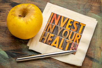 Wall Mural - invest in your health concept - word abstract in vintage letterpress wood type on a napkin with apple, healthy lifestyle advice