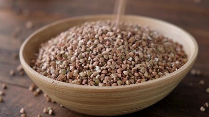 Wall Mural - Buckwheat groats falling in a wooden bamboo bowl. Healthy food