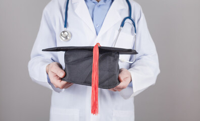 Wall Mural - Caucasian doctor holding graduation hat. Medical education