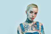 Close Up Of A White Tattooed Woman With Piercing Looking Into A Camera With Her Head Slightly Tilted