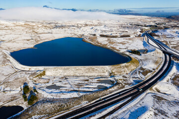Poster - Aerial view of a large reservoir next to a major dual carriageway on a snowy day