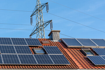 solar panels on roof of house next to electricity pylon 