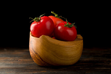 tomatoes in a wooden basket on a dark wooden background