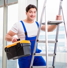 Wall Mural - Young repairman climbing ladder at construction site