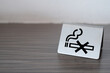 close-up the iron plate of no smoking sign on the wooden table. No Smoking label in the public. Selected focus.