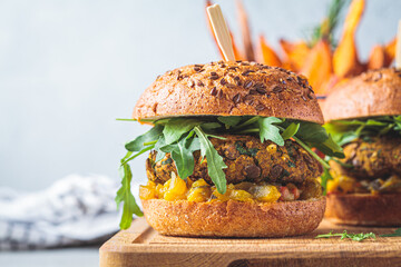 Canvas Print - Vegan lentil burger with arugula, mustard sauce, fresh vegetables and sweet potato fries on wooden board. Vegan food concept.