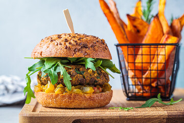 Canvas Print - Vegan lentil burger with arugula, mustard sauce, fresh vegetables and sweet potato fries on wooden board. Vegan food concept.