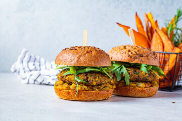 Vegan lentil burger with arugula, mustard sauce, fresh vegetables and sweet potato fries, copy space. Vegan food concept.