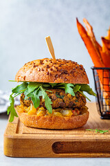 Canvas Print - Vegan lentil burger with arugula, mustard sauce, fresh vegetables and sweet potato fries on wooden board. Vegan food concept.