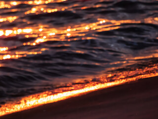 Wall Mural - Golden sunset light reflection in dark water, purposely blurred background with photographic bokeh effect