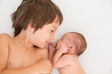 Poster - Beautiful boy, hugging with tenderness and care his newborn baby brother at home