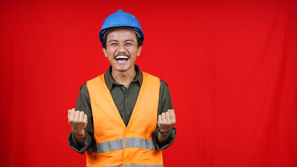 Handsome asian worker man wearing uniform, helmet, safety harness over isolated red background celebrating surprised and amazed for success with arms raised and open eyes. Winner concept