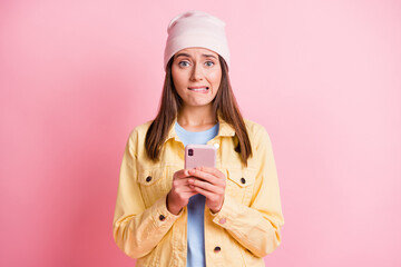 Canvas Print - Portrait of worried young woman hold phone wear yellow jacket post mistake comment isolated on pink color background