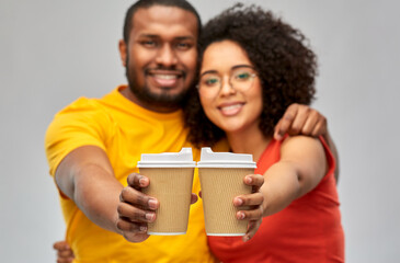 Wall Mural - relationships and people concept - happy smiling african american couple with takeaway coffee cups over grey background