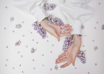 Wall Mural - Natural woman cosmetics for hands made of lilac flowers and petals. Moisturize and soften the skin of the hands. Lilac flowers protrude from the sleeves of the arm