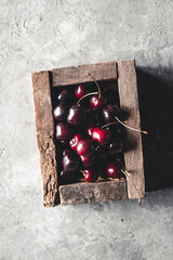 Wall Mural - Wooden box with sweet cherry on blue background. Place for text.