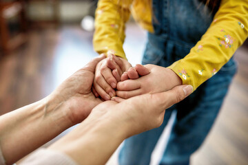 I care about you. Close up shot of grandmother holding hands of her little granddaughter while spending time together indoors