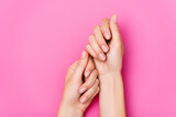 top view of female hands with pastel nail varnish on fingernails on pink background