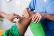 © LIGHTFIELD STUDIOS - cropped view of african american sportsman pointing with finger at injured knee near doctor